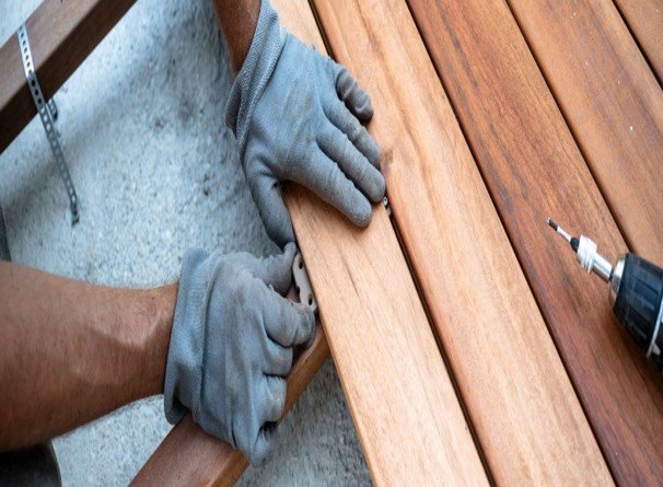 Contractor installing wood porch boards with a drill during a residential porch construction project.