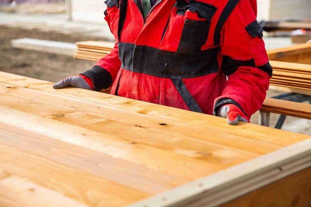 Deck installer inspecting and positioning wood boards during professional deck installation