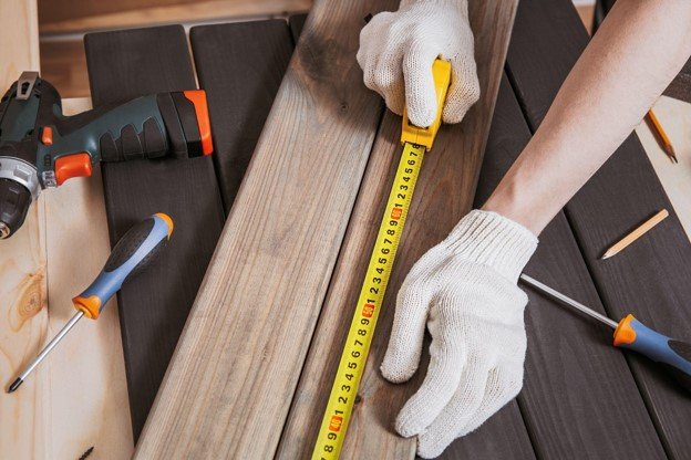 Contractor measuring deck boards with a tape measure during a residential deck installation