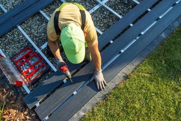 Contractor installing dark composite deck boards over a metal frame during custom deck construction