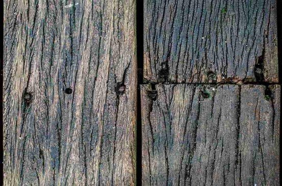 Close-up of old weathered wood deck boards with cracks and deterioration before replacement