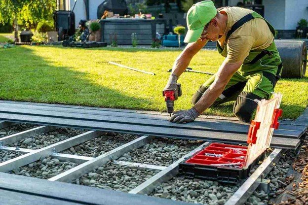 Deck installer securing composite decking boards over a metal frame during deck installation in Rowlett, TX