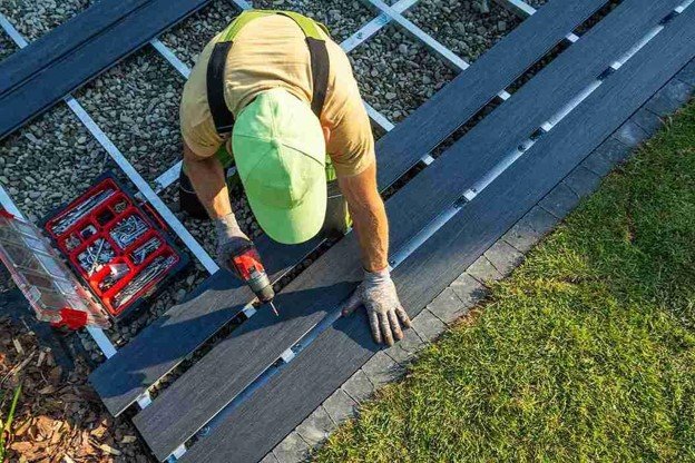 A professional drilling a on wood working n trex deck installation.