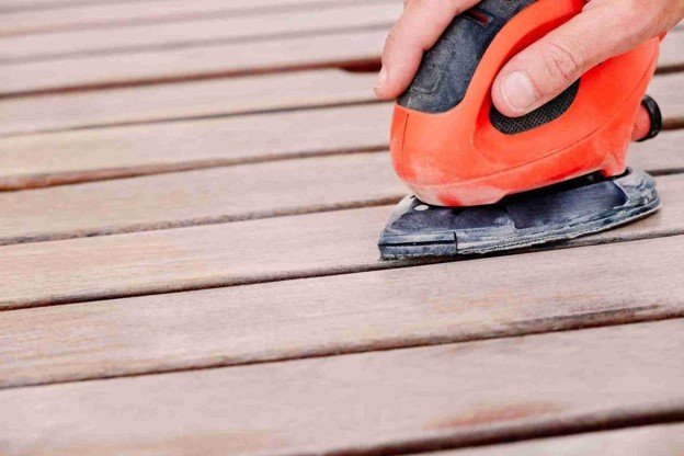 Power sander removing the worn surface from wood deck boards during deck cleaning and restoration in Rowlett, TX
